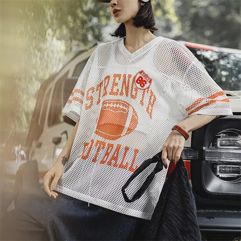 Person wearing a white mesh sports jersey with orange text and graphics, standing outdoors.